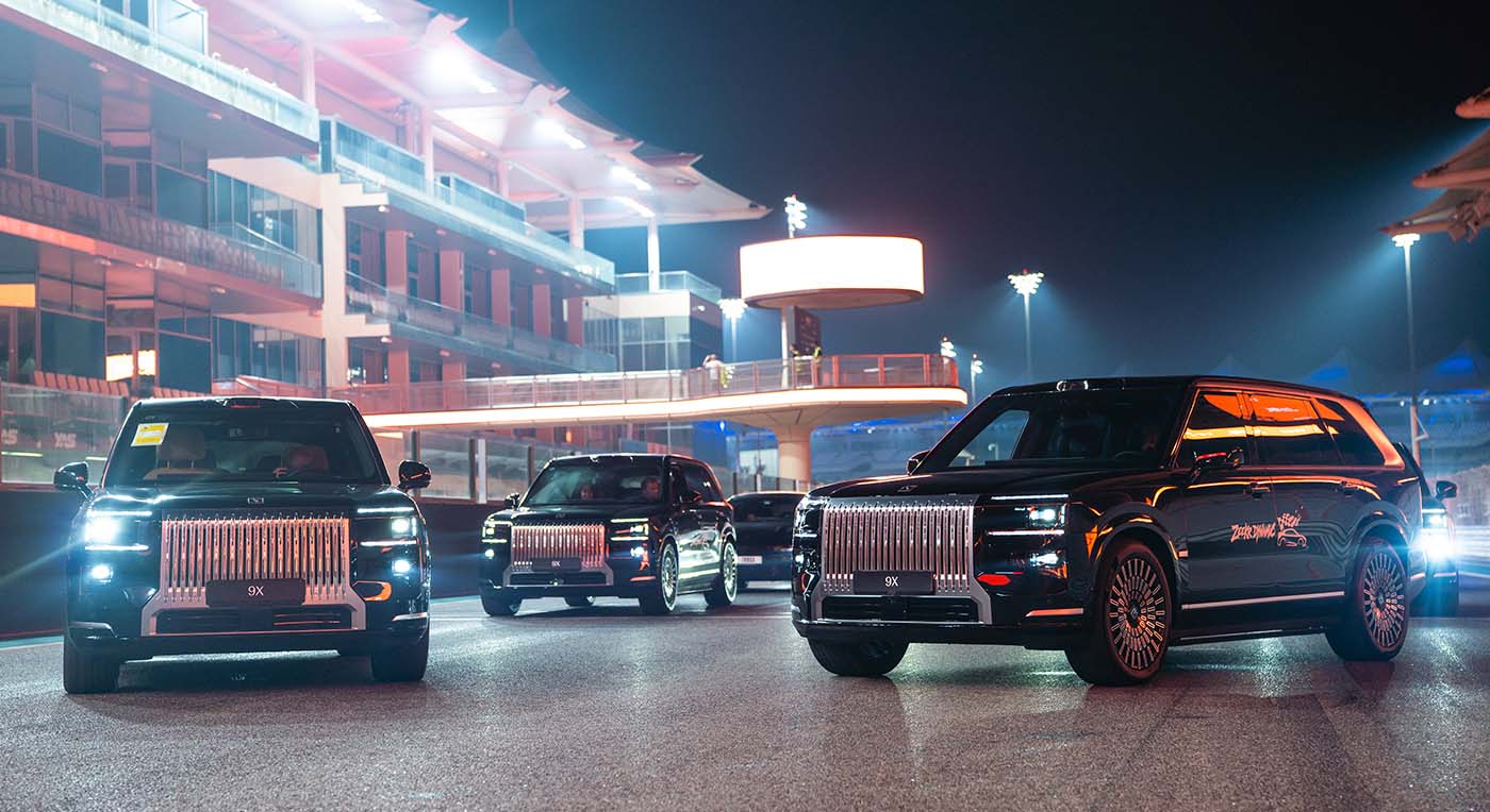 Three black luxury Zeekr 009 SUVs showcased on an illuminated night race track under bright stadium lighting